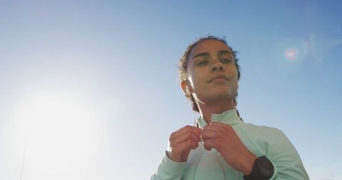Confident runner preparing with earphones in bright sunshine