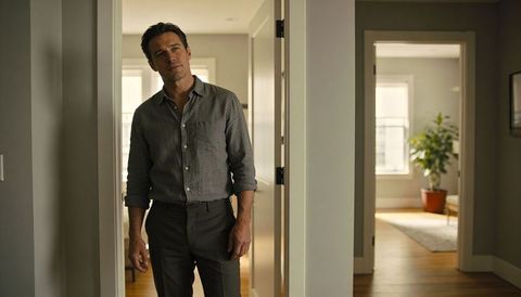Pensive man standing in doorway of minimalist modern home with natural light and houseplant