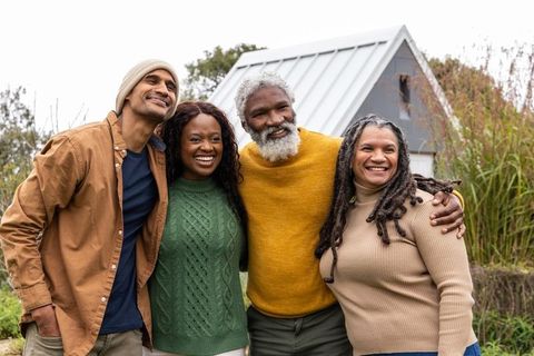 Hugging multigenerational friends in garden wearing knit sweaters and beanie