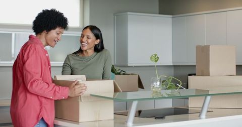 Joyful couple unpacking boxes in modern kitchen