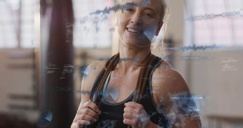 Smiling fit woman holding jump rope during cardio training with digital waveform overlay