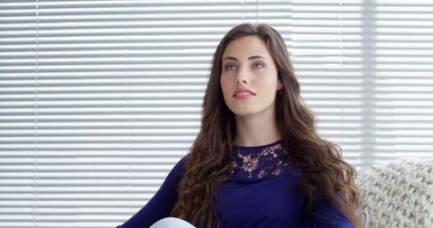 Thoughtful woman sitting indoors near window