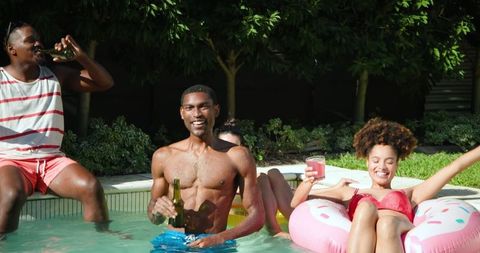 Diverse Friends Relaxing Together in Backyard Pool on Summer Day