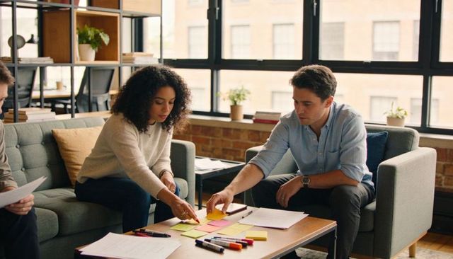 Team organizing sticky notes during brainstorming session in modern office lounge