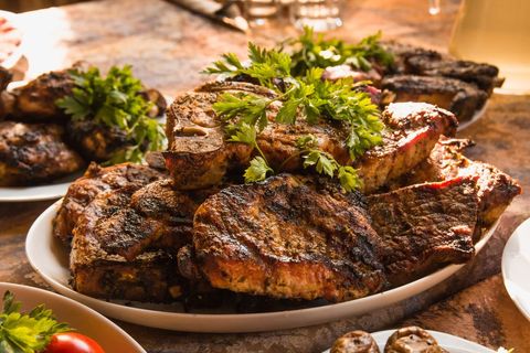 Heaping Platter of Grilled Steaks with Parsley Garnish on Rustic Table for Barbecue