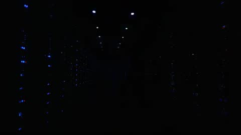 Dolly moving down data center aisle showing glowing blue server LEDs and deep perspective