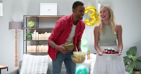 Cheerful couple tidying up after house party celebration