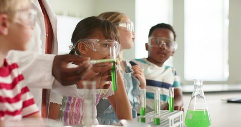 Young students learning chemistry while teacher guides pipette and test tube experiments