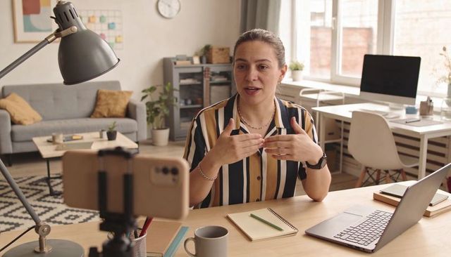 Remote presenter gesturing during live video coaching in cozy modern home office workspace
