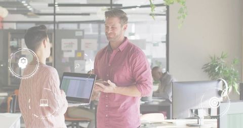 Smiling professional collaborating with colleague over spreadsheet in modern open-plan office