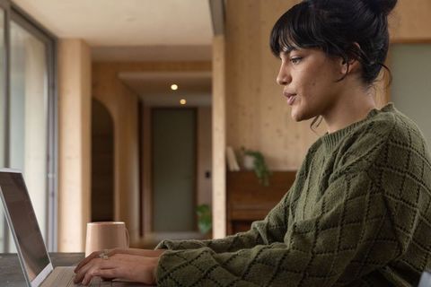 Asian Woman Typing on Laptop in Cozy Domestic Scene