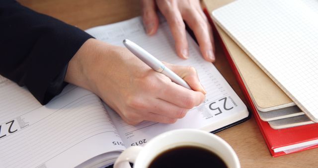 Person Writing in Planner with Coffee on Desk - Download Free Stock Images Pikwizard.com