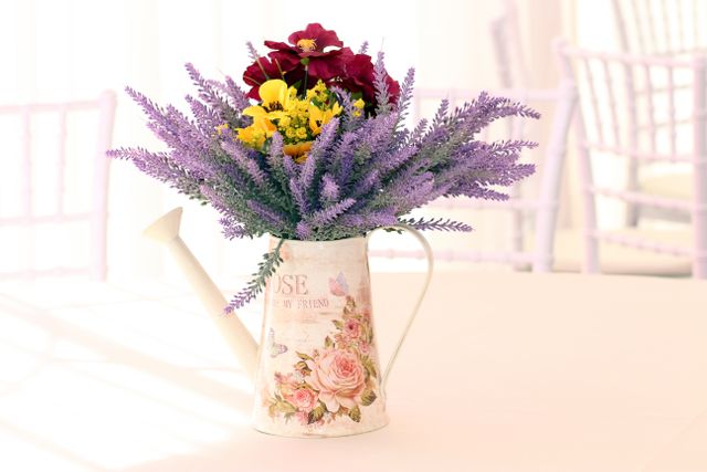 Bright flower arrangement featuring lavender and mixed flowers beautifully displayed in a vintage watering can, creating a charming and rustic feel. Ideal for use in home decor inspirations, interior design blogs, wedding reception decor ideas, and lifestyle magazines.