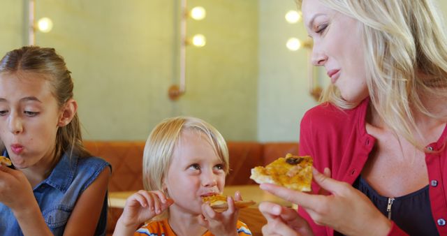 Mother Enjoying Pizza with Children in Cozy Restaurant - Download Free Stock Images Pikwizard.com