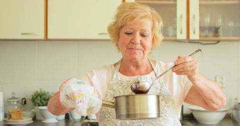 Senior woman crafting homemade jam in rustic kitchen