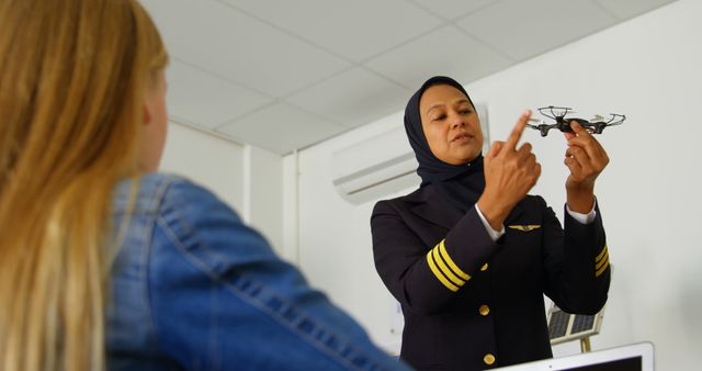 Female pilot explaining drone mechanics to engaged student in classroom, promoting female representation in aviation and STEM programs. Ideal for educational materials, articles on women in tech, and resources on aviation careers.