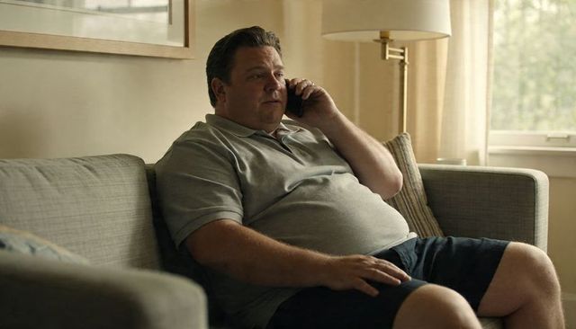 Middle-aged man relaxing on sofa, making phone call in sunlit contemporary living room