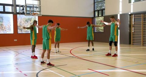 Multicultural Basketball Team Stretching in Gymnasium