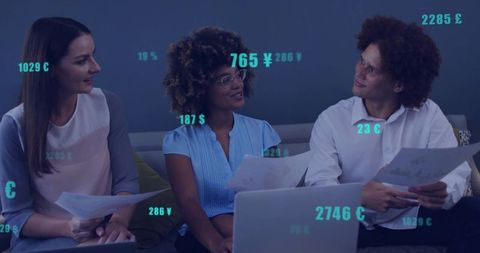 Reviewing financial data on laptop with teal currency overlays during collaborative team meeting