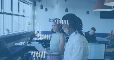 Collaborating in modern coworking space reviewing laptop and documents for project planning