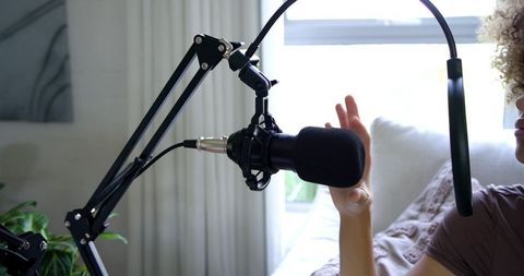 African american woman speaking into microphone in bright home podcast studio