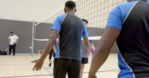 Diverse Male Volleyball Team Shaking Hands at Net in Gym During Practice Session with Unity