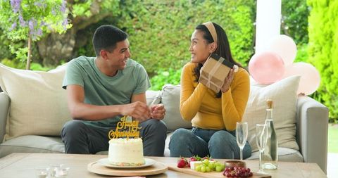Joyful birthday celebration with young couple exchanging gifts