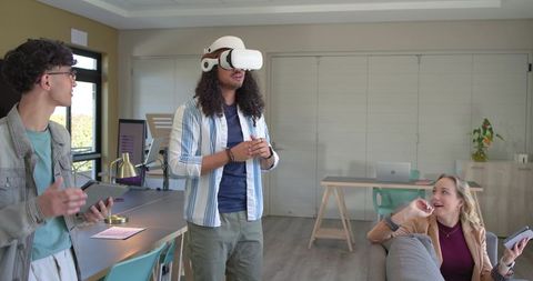 Multicultural team testing VR headset while collaborating in modern office lounge