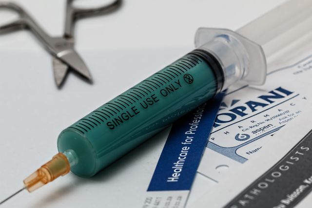 This stock photo shows a close-up of a medical syringe labeled 'Single Use Only' placed on a document. Useful for website articles, medical blogs, healthcare promotions, vaccination awareness, studies on medical equipment or patient care tutorials.