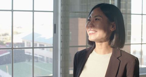 Confident businesswoman laughing in sunlit office