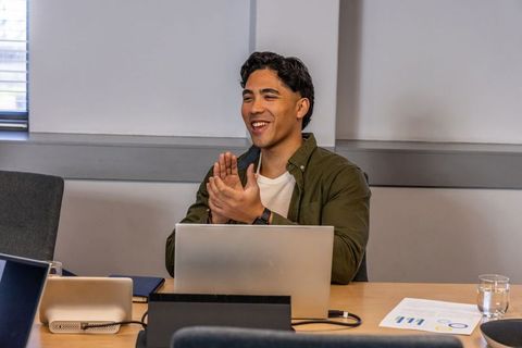 Young professional clapping during team meeting using laptop and reviewing charts