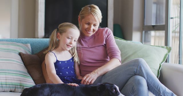 Happy caucasian mother and daughter sitting on sofa together and petting dog at home - Download Free Stock Photos Pikwizard.com