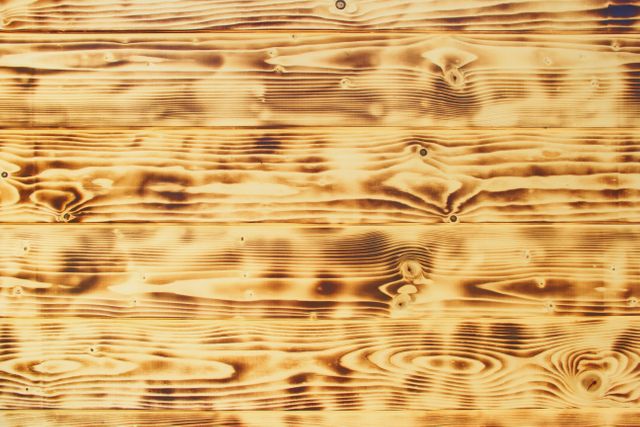 Burnt wood texture shows unique grain patterns in warm shades. Ideal for backgrounds, web design, interior design inspiration, crafting materials, or rustic-themed projects.