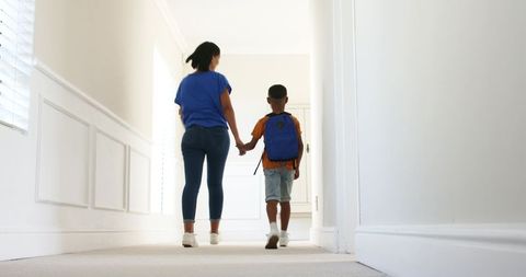Mother and child walking hand in hand down hallway