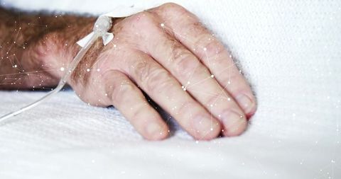 Senior patient hand resting on hospital bed with IV catheter and digital health network overlay