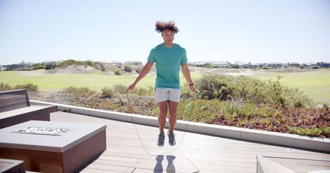 Young Woman Skipping Rope Outdoors in Sunny Backyard