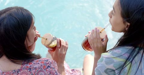Teen Girls Enjoying Iced Tea by Pool on Sunny Day