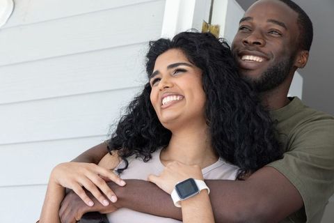 Multicultural couple embracing at doorway, indian woman and african american man smiling