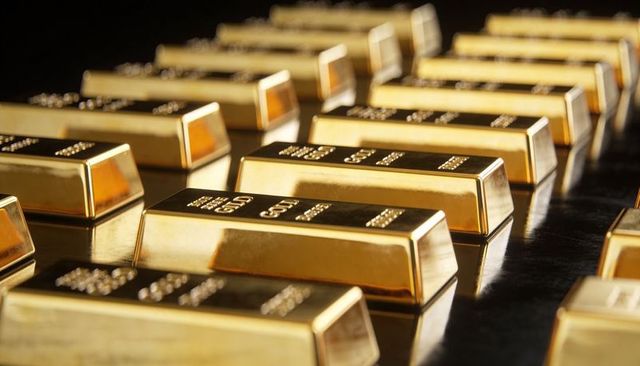 Rows of gleaming gold bullion bars resting on shiny black surface reflecting luxury wealth