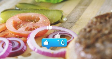 Red onion rings and tomato on cutting board with pickle, burger bun and like icon overlay
