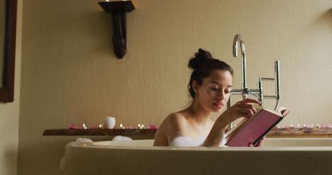 Woman Relaxing in Bubble Bath Reading Book