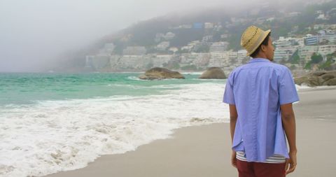 Young Man Walking by Ocean Surrounded by Foggy Coastal City - Download Free Stock Images Pikwizard.com