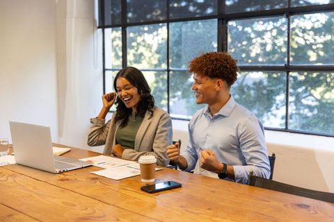 Celebrating team success during video call in bright modern conference room