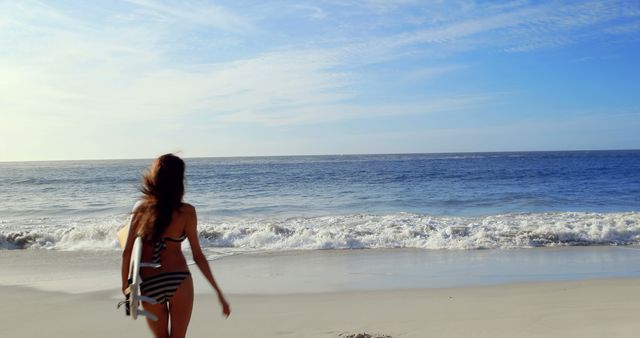 Happy brunette walking with surfboard at the beach