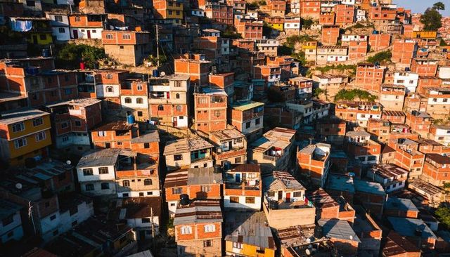 Sunlit brick houses clinging to steep urban hillside with corrugated roofs and water tanks