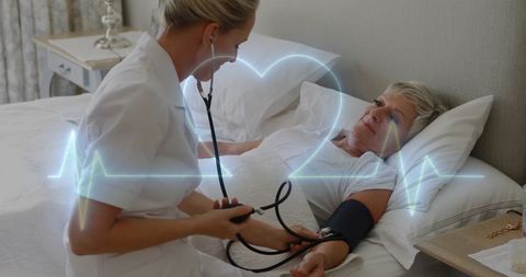 Nurse checking blood pressure of elderly patient at hospital bedside