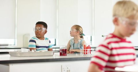 Elementary students conducting science experiment wearing safety goggles at lab bench