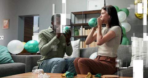 Couple inflating green balloons preparing cozy living room celebration and diy decor ideas