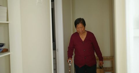 Senior woman using walking stick indoors reflecting independence