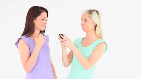 Excited Young Women Using Smartphone in Bright Studio